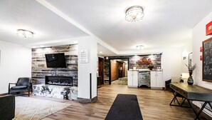 A modern living room with a fireplace, a mounted TV, and a dining area with a table and chairs. - Managed by Park City Lodging-Steps Away From Town Lift AND Main Street! (PARK CITY)