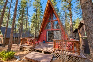 Une cabane à l’extérieur rouge, dotée d’une terrasse en bois et d’une grande fenêtre.