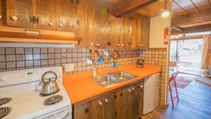 A kitchen with wooden cabinets, a white stove, an orange countertop, and a stainless steel sink. - A-Frame of Mind - Wood Stove Fireplace, Deck, Barbecue (Big Bear City)