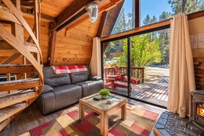 Un interior acogedor de cabaña con un sofá, una mesita y una chimenea.