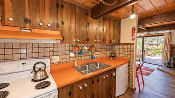 Una cocina con armarios de madera, una estufa blanca y un lavamanos.