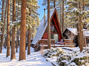 Une cabane au toit très pentu, entourée de grands pins et recouverte de neige.