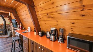 Una cocina con paredes y techo de madera, una barra y un horno empotrado.