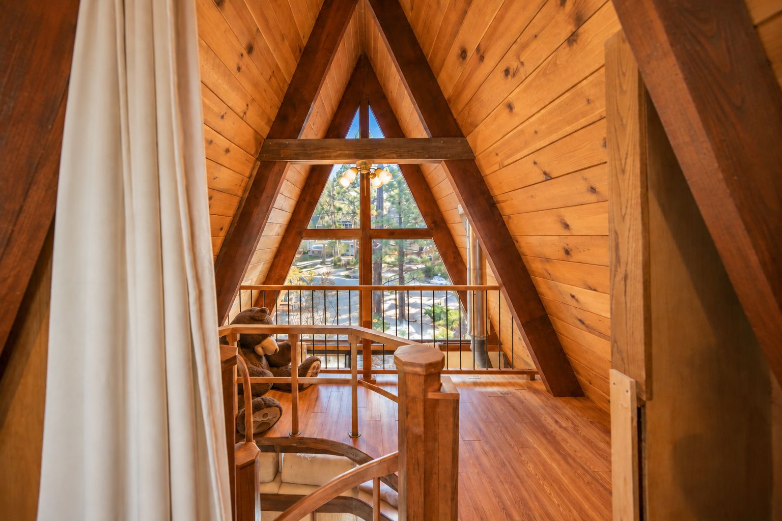 A wooden interior with a wooden staircase leading to a balcony.