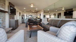 A modern living room with a sofa, chairs, a coffee table, and a kitchen in the background. - BT504 | Short Walk to Base Area | Views | Winter Shuttle | Pool/Hot Tub | Ski In (Steamboat Springs)