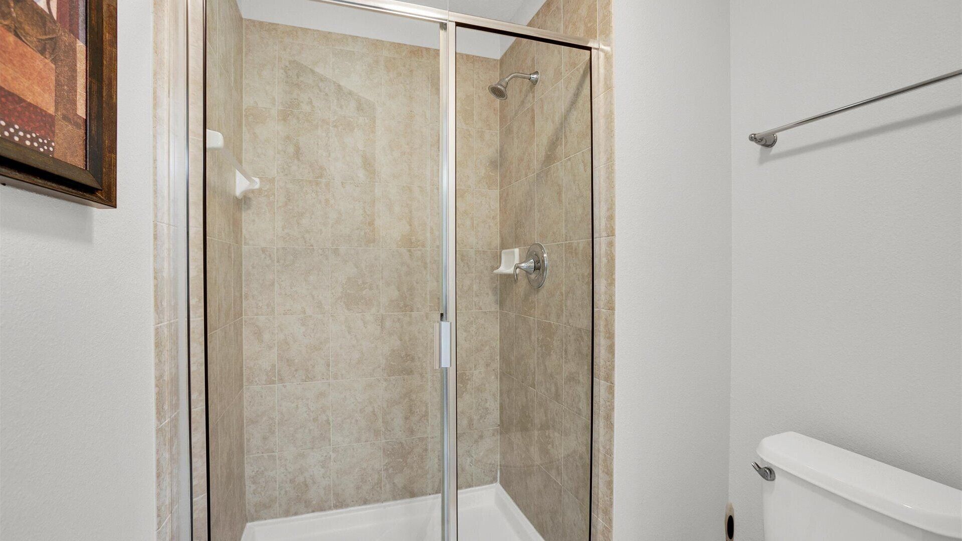 Eine Duschkabine mit Glaswänden, eine weiße Badewanne und ein WC in einem Badezimmer.
