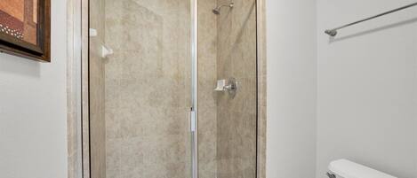 Eine Duschkabine mit Glaswänden, eine weiße Badewanne und ein WC in einem Badezimmer.