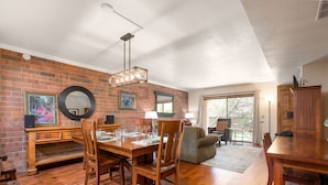 Un comedor con pared de ladrillo, muebles de madera y una araña.