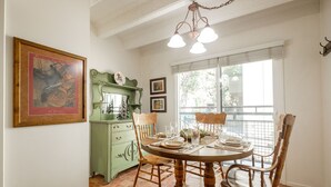 A dining area with a round wooden table set for four, surrounded by wooden chairs. A green cabinet with a decorative top is to the left, and a window with blinds is behind the table. - Walk from Park City Lifts to Heated Pool/Hot Tub Managed by Park City Lodging (Park City)