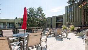 An outdoor patio area with tables and chairs, a red umbrella, and a barbecue grill. - Walk from Park City Lifts to Heated Pool/Hot Tub Managed by Park City Lodging (Park City)