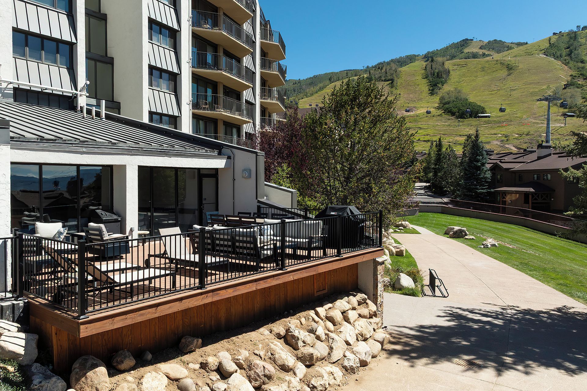 Een modern hotel met een terras, zitplaatsen buiten en uitzicht op een bergachtig landschap.