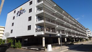 Ein mehrstöckiges Hotel mit Balkonen, einem Parkplatz und blauem Himmel.