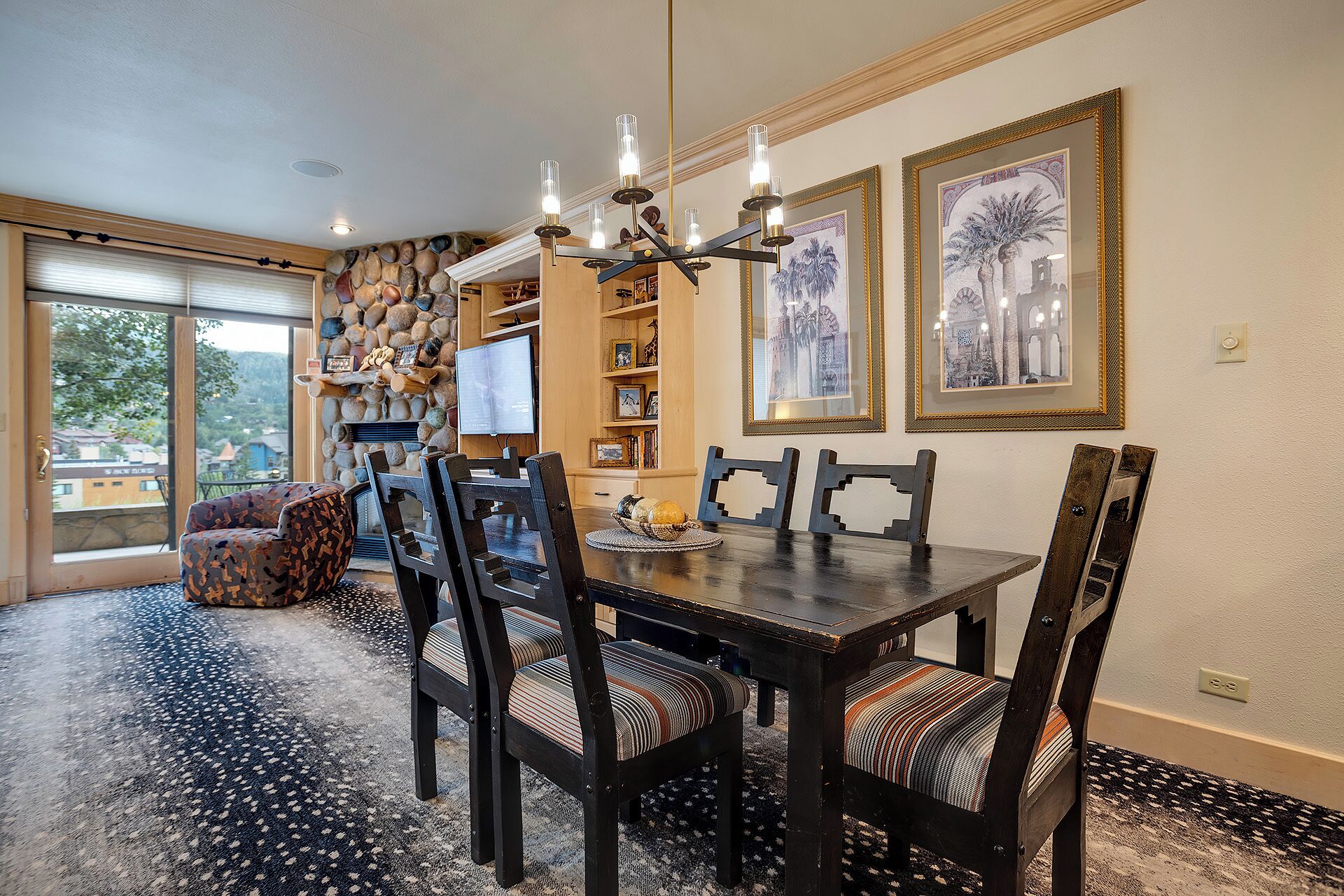 A dining area with a wooden table and chairs, a stone wall, and a television.
