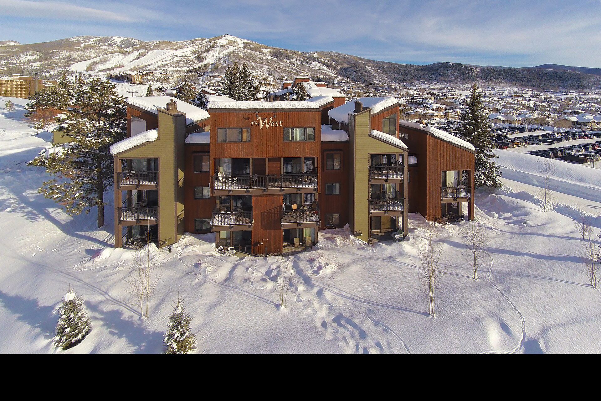 A multi-story building with balconies, surrounded by snow-covered terrain and mountains in the background.