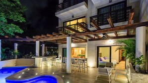 A modern hotel with a swimming pool, outdoor seating area, and a well-lit entrance. - Completely Renovated with Private Pool WIFI (Playa del Carmen)
