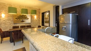 A modern kitchen with granite countertops, a stainless steel refrigerator, and a dining area with dark wood furniture. - Completely Renovated with Private Pool WIFI (Playa del Carmen)