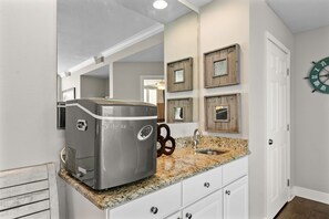Una cocina con estufa integrada, encimera de granito, armarios blancos y protector de salpicadura de madera.