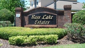Un panneau indiquant l’entrée de la résidence Bass Lake Estates, avec une arche en briques et des jardins bien entretenus.