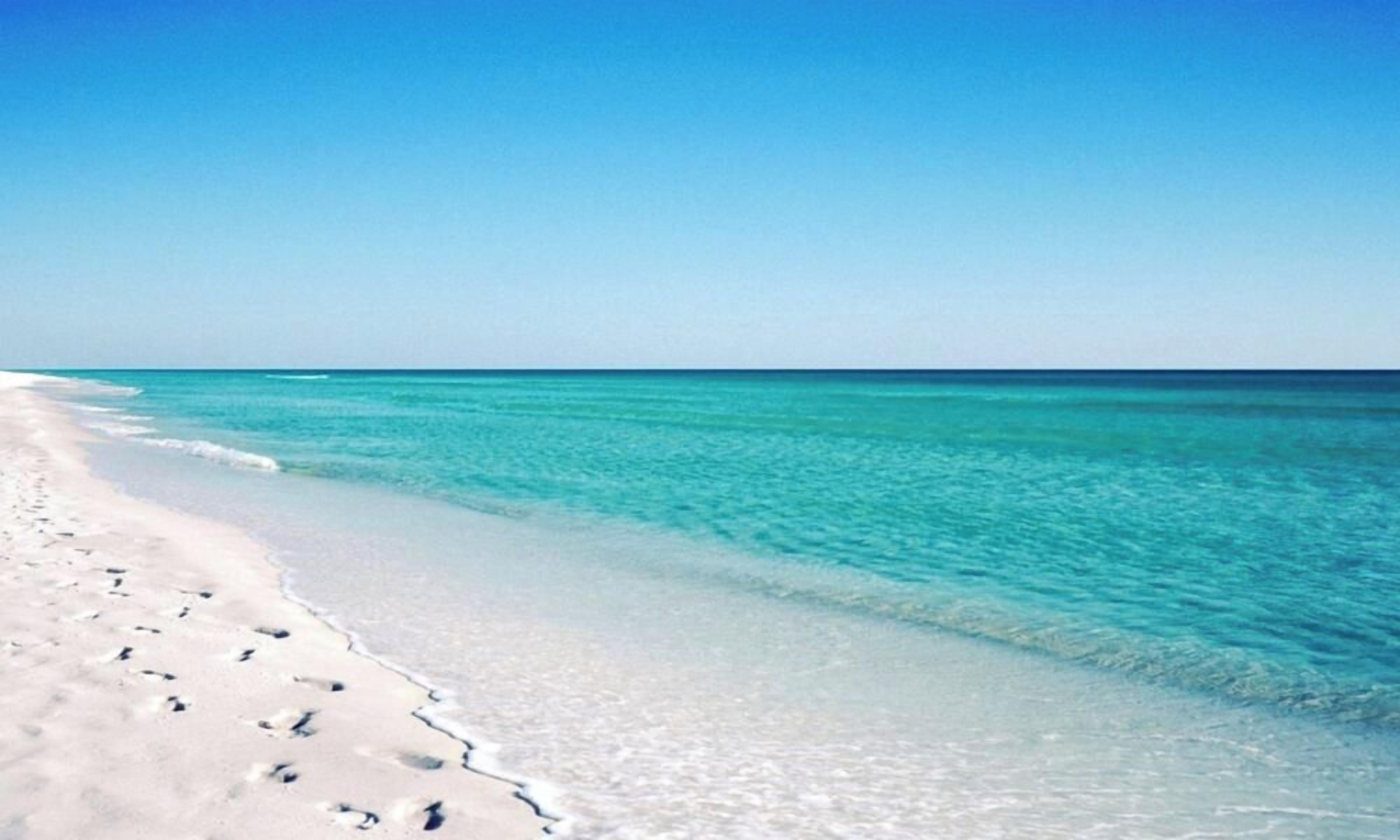 Una playa con agua turquesa cristalina y arena blanca.