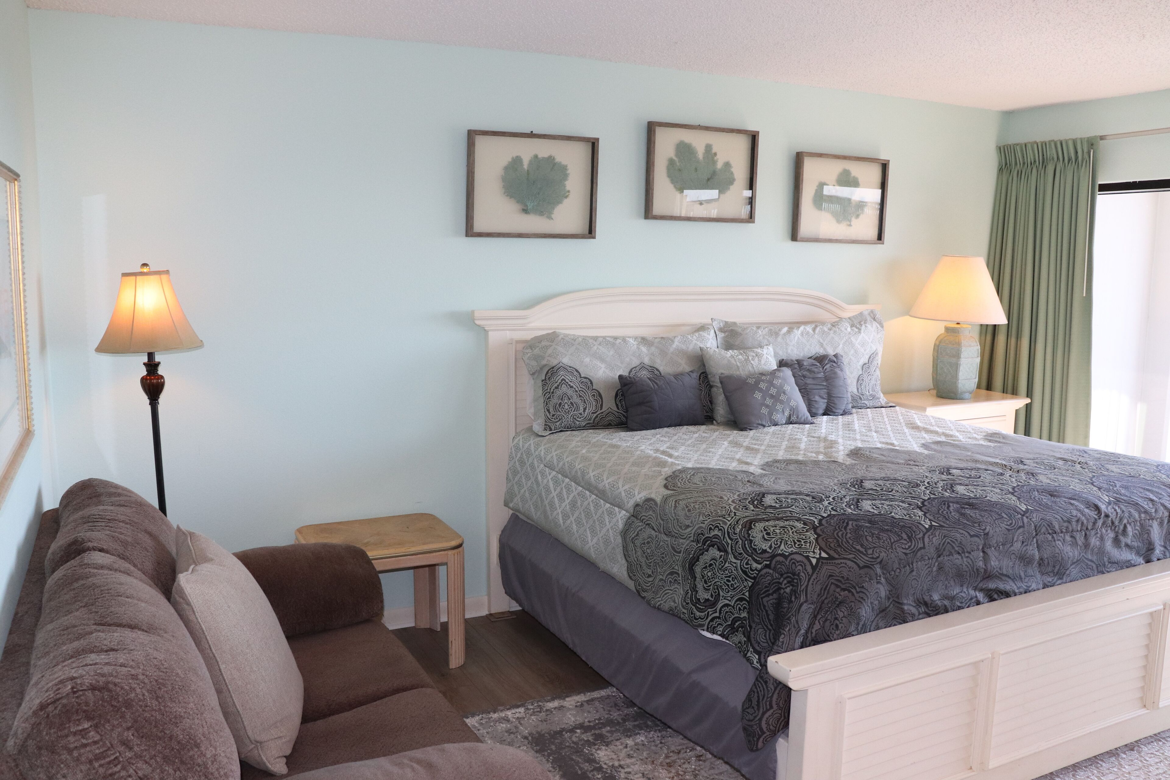 A bedroom with a bed, bedside tables, a lamp, and framed artwork on the wall.