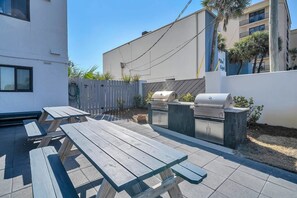 Un patio con mesas de picnic y una parrilla.