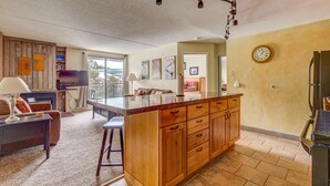 A spacious living area with a wooden island, a flat-screen TV, and a dining table. - Trails End 509, Breckenridge (Breckenridge)