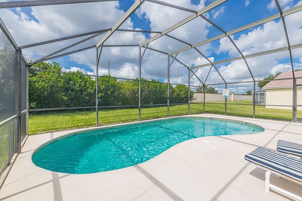 A covered swimming pool with a curved edge, surrounded by a metal frame and glass panels.