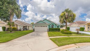 A residential street with houses featuring front garages, well-maintained lawns, and palm trees.