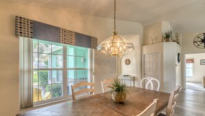 A dining area with a wooden table, chairs, and a hanging light fixture.
