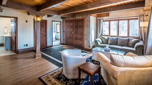 A spacious living room with a wooden ceiling, a stone fireplace, a sofa, and a coffee table. - Breathtaking Mt Washington Views  Jackson Chalet (Jackson)
