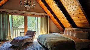 A bedroom with a large bed, a chair, a chandelier, and a view of the outdoors. - Breathtaking Mt Washington Views  Jackson Chalet (Jackson)