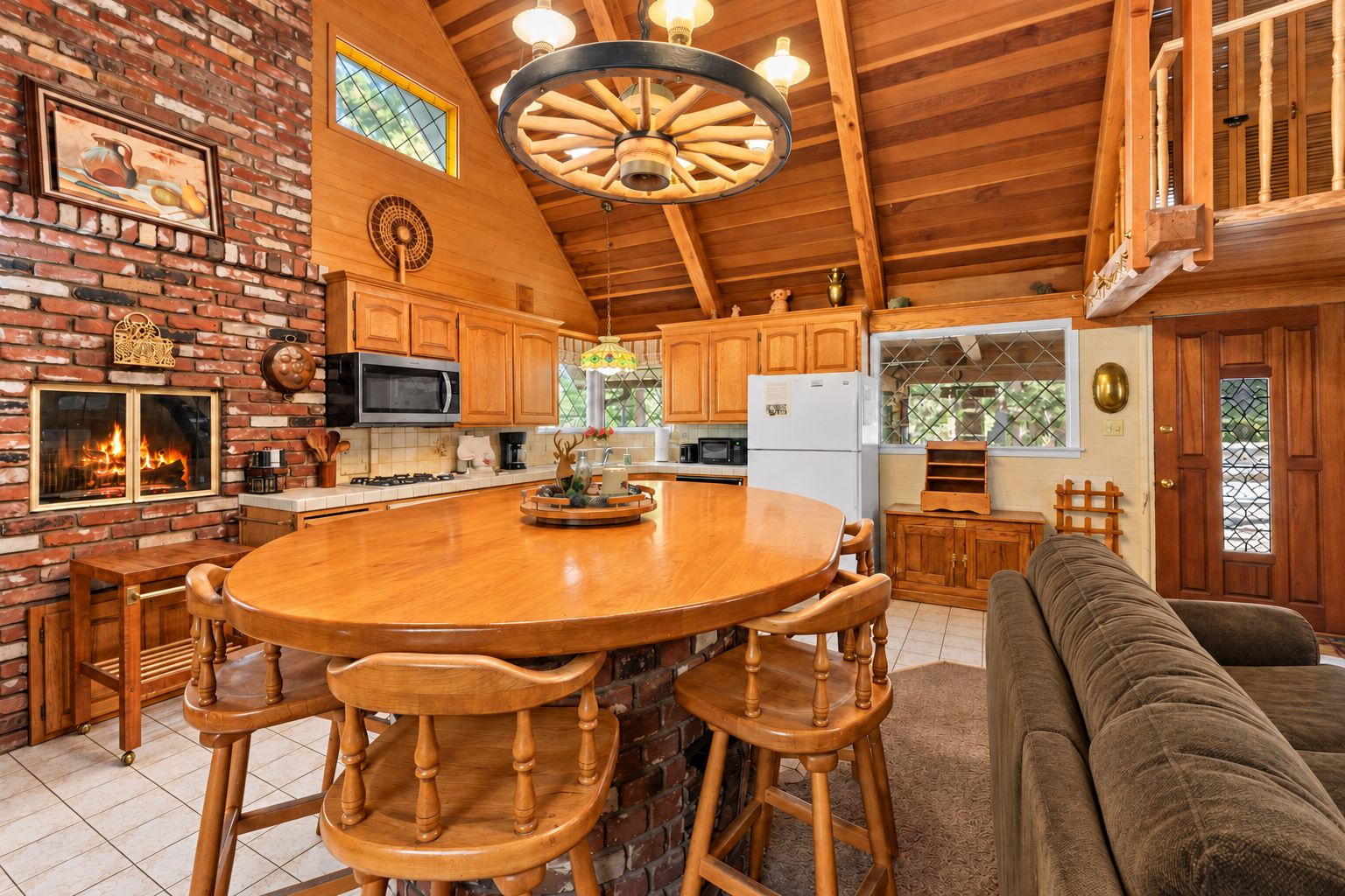 Una cocina con isla central, armarios de madera, microondas y refrigerador.