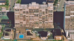 Un immeuble résidentiel de grande hauteur doté de nombreux balcons, d’un parking et d’une piscine.