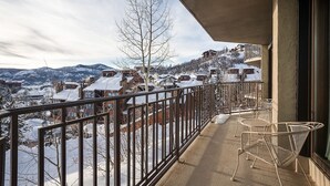A balcony with a metal railing overlooking a snow-covered village with houses and mountains in the background. - BT202 | Great Mountain Escape | Ski In | Close to Base Area | Winter Shuttle (Steamboat Springs)