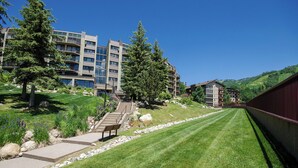 A modern hotel with multiple floors, outdoor seating, and a well-maintained lawn. - BT202 | Great Mountain Escape | Ski In | Close to Base Area | Winter Shuttle (Steamboat Springs)