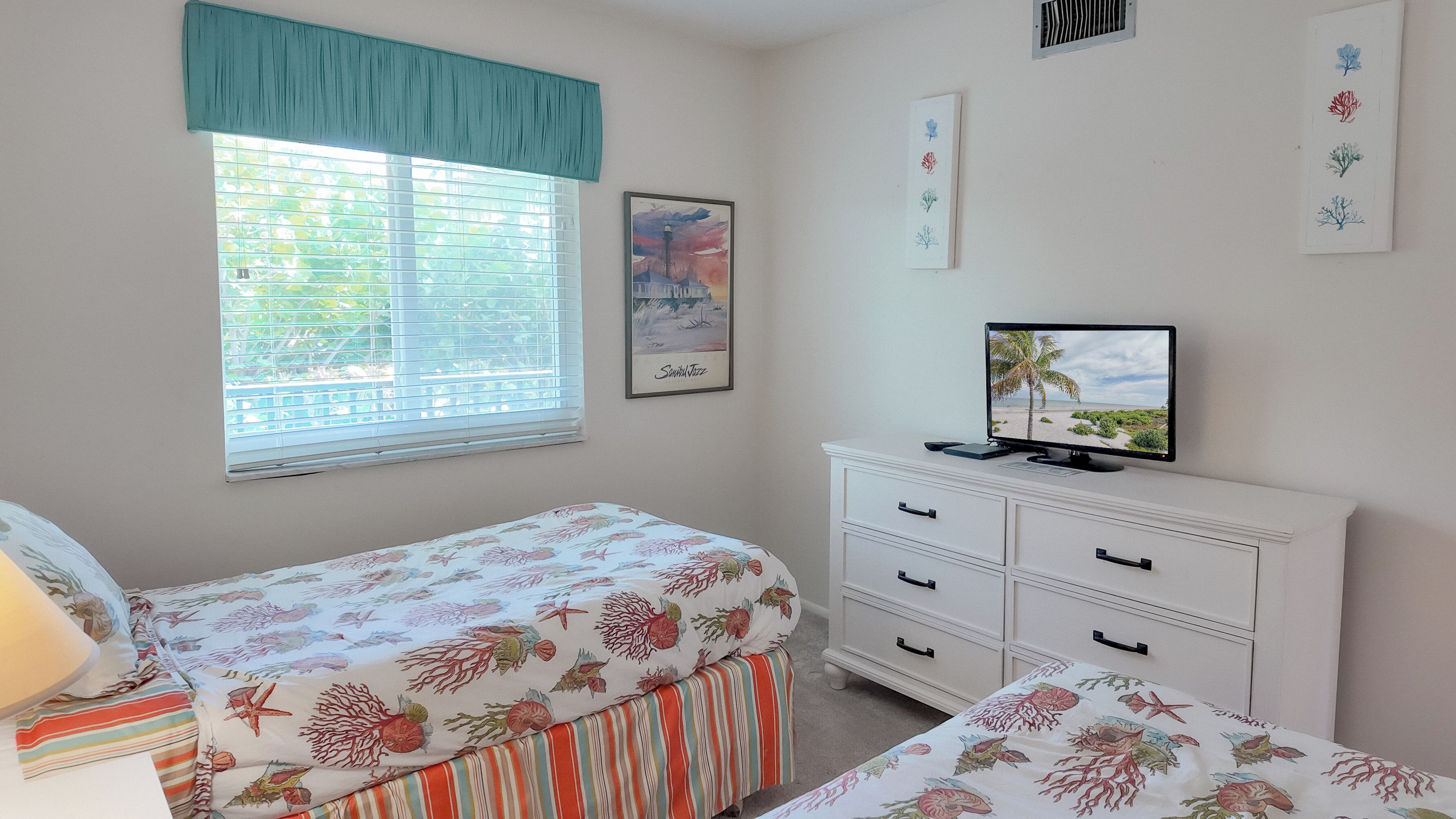 Un dormitorio con cama, cómoda, televisor y ventana con persianas.