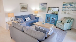 A living room with a sofa, a coffee table, a TV, and a chair. - Serene and Relaxing (Sanibel)
