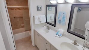 A bathroom with two sinks, a large mirror, and a shower area. - Serene and Relaxing, Sanibel Siesta Unit #702 (Sanibel)