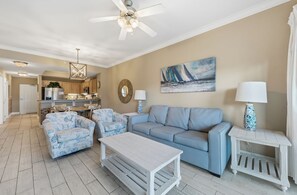 Un salon comprenant un canapé, deux fauteuils, une table basse et un ventilateur de plafond.