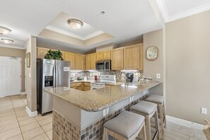 A modern kitchen with a central island, stainless steel appliances, and wooden cabinets.