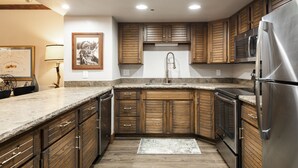A kitchen with wooden cabinets, stainless steel appliances, and a granite countertop.