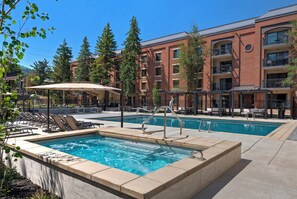 Ein Hotel mit Swimmingpool, Liegestühlen und Blick auf Bäume und Gebäude.