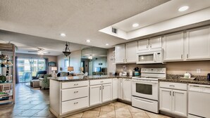A spacious kitchen with white cabinets, a granite countertop, and a large island. - El Matador 413 by Alicia Hollis Rentals FREE TICKETS! $300/Day (Fort Walton Beach)