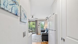 A hallway leading to a living area with a ceiling fan, a refrigerator, and artwork on the walls. - Oceanside Oasis - Breathtaking Views and Coastal Comfort! (Hilton Head)