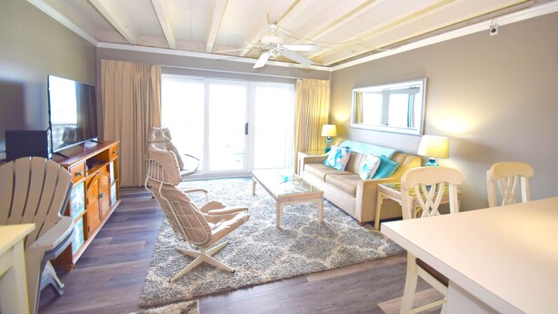 A living room with a sofa, chairs, a coffee table, a TV, and a ceiling fan. - Jada 4H-Oceanside 77th St, Free WiFi, Pool, Elev, W/D, AC (Ocean City)