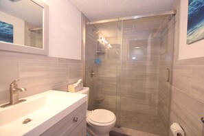 Ein modernes Badezimmer mit einer Duschkabine aus Glas, einem weißen Waschbecken und einer Toilette.