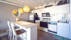 A modern kitchen with white cabinetry, a central island, and pendant lighting. - Jada 4H-Oceanside 77th St, Free WiFi, Pool, Elev, W/D, AC (Ocean City)
