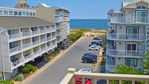 A beachfront hotel with multiple balconies, a parking area, and a view of the ocean. - Jada 4H-Oceanside 77th St, Free WiFi, Pool, Elev, W/D, AC (Ocean City)