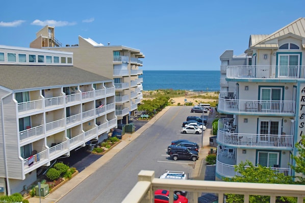 Ein Hotel direkt am Strand mit mehreren Balkonen, einem Parkplatz und Blick auf das Meer.