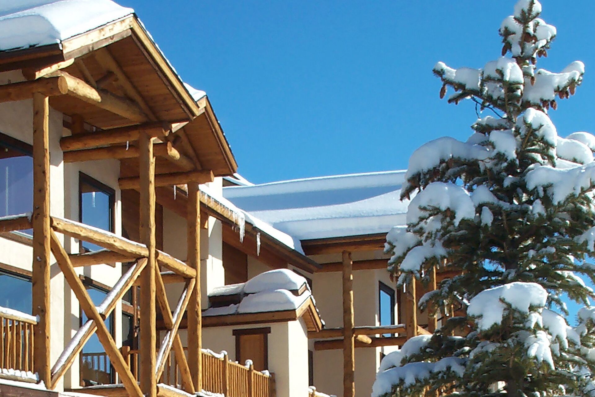 A wooden chalet with a balcony and snow-covered roof.